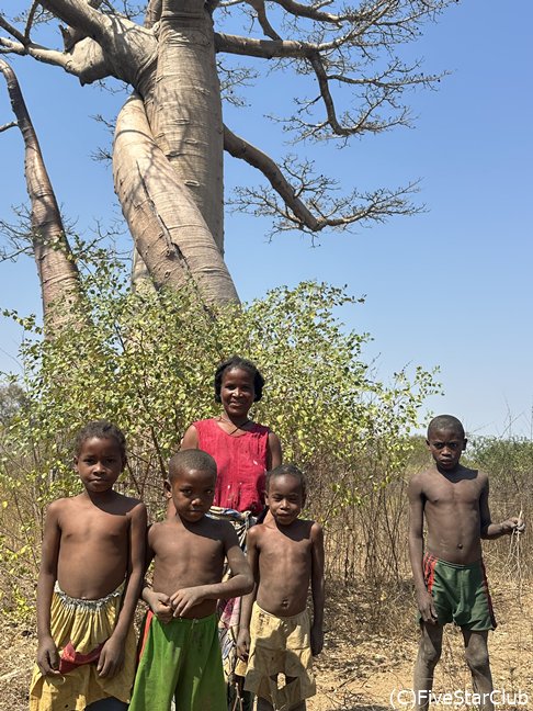 ユニークな形のバオバブの前で車に近付いてきた家族