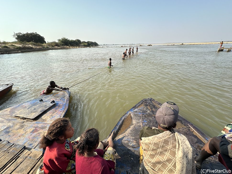 筏に車を乗せて、人がみんなでロープで引っ張ります